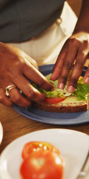 Hands, house and woman with sandwich, kitchen and healthy meal with food, diet plan and ingredients. Bread, apartment and person with nutrition, wellness and lunch with tomatoes, hungry and lettuce
