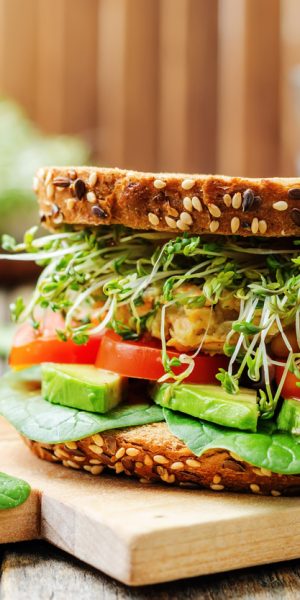 sprouts avocado tomato spinach chickpeas burger rye sandwich. toning. selective focus